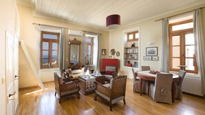Una habitación amplia con piso de madera, una zona de comedor con mesa y sillas, un armario rojo y un ventanal con vistas.