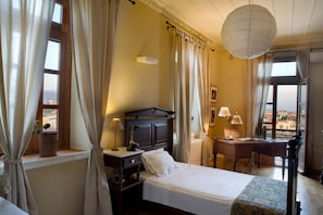 A bedroom with a bed, a desk, and a view of the city. - Dorothy's Dream (Chania)