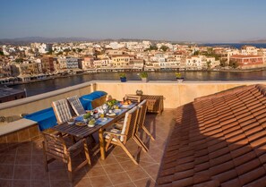 A terrace with a table set for dining, overlooking a river and a cityscape. - Dorothy's Dream (Chania)