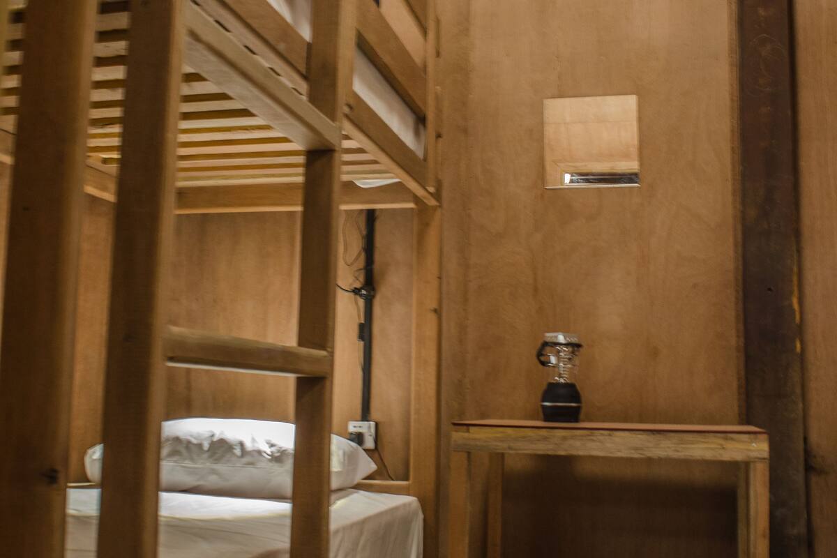 A wooden bunk bed room with a small table and a shelf.
