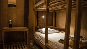 A bunk bed room with a wooden headboard, a small table with a blender, and a single light fixture. - Hardwood Lodge - Hostel (Nyaungshwe)