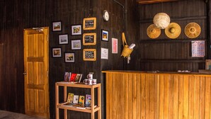 A wooden reception desk with a shelf of books and a basket. - Hardwood Lodge - Hostel (Nyaungshwe)