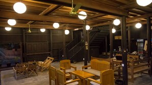 A spacious indoor area with wooden furniture, including tables and chairs, and a staircase leading to an upper level. - Hardwood Lodge - Hostel (Nyaungshwe)