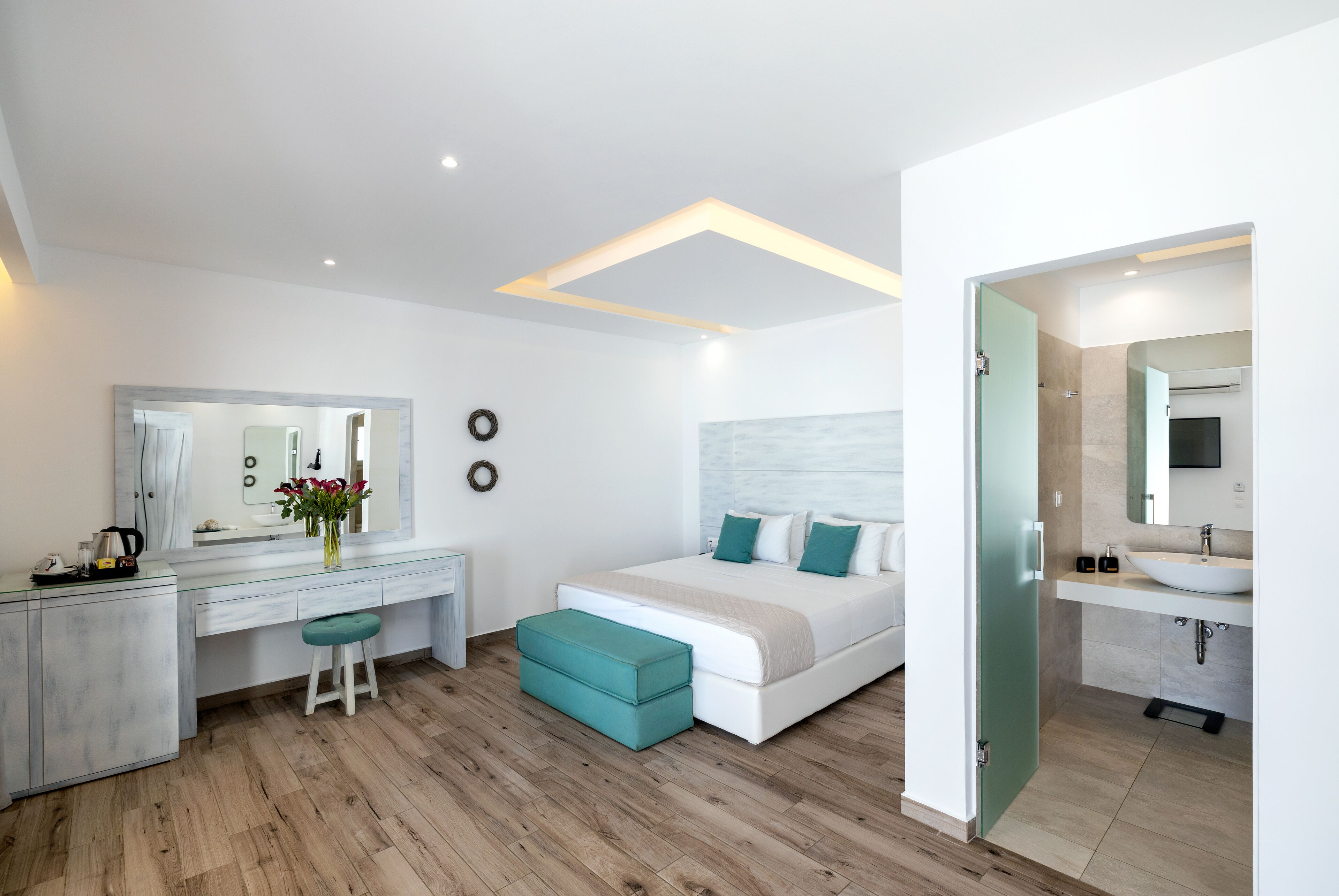 Une chambre moderne avec un grand lit, une coiffeuse avec un miroir et un bureau.