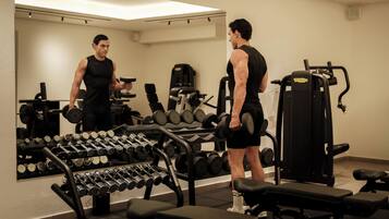 A gym with exercise equipment, benches, and a mirror.