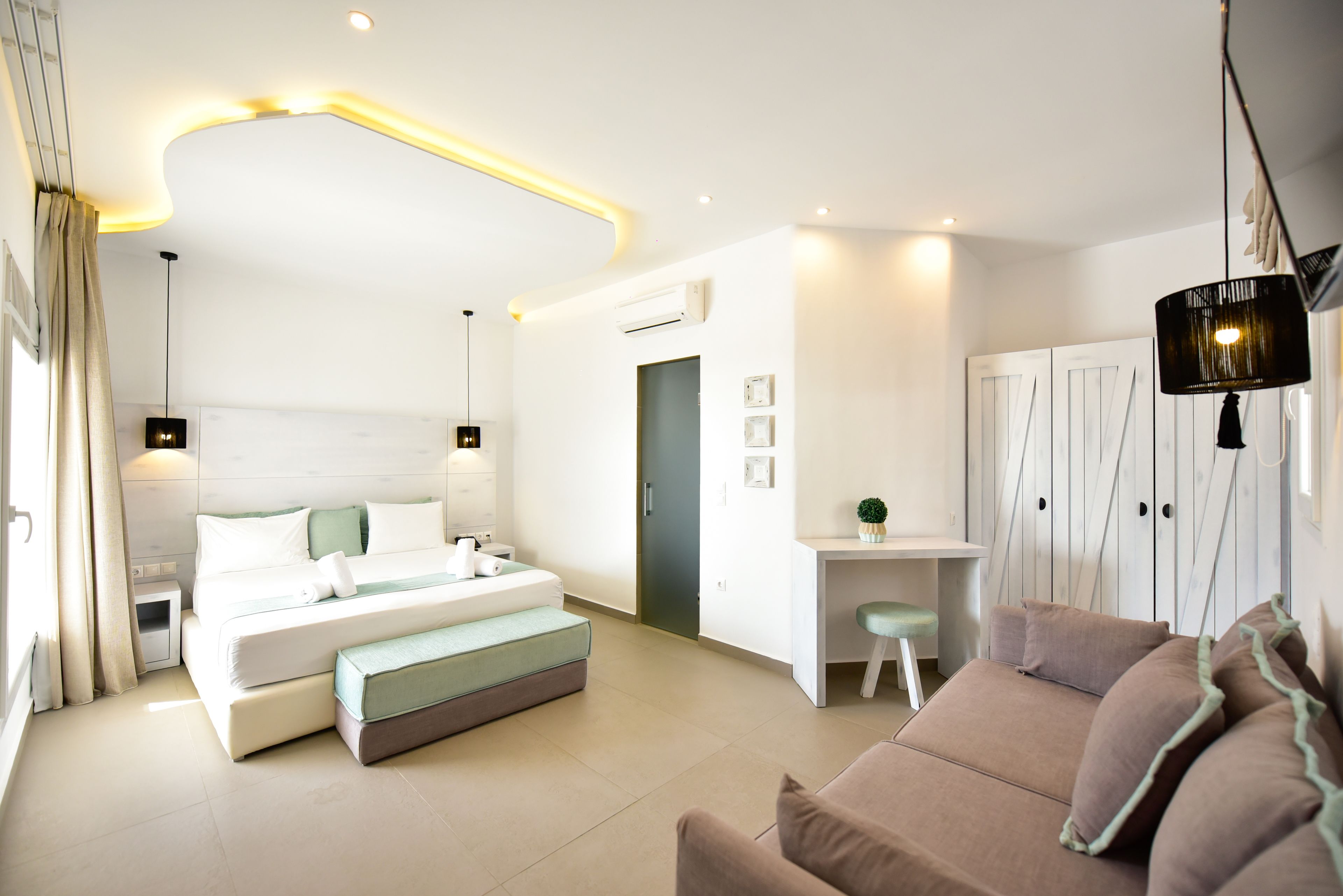 Une chambre d’hôtel moderne dot ée d’un grand lit, d’un coin salon avec un canapé, d’un bureau et d’une armoire.