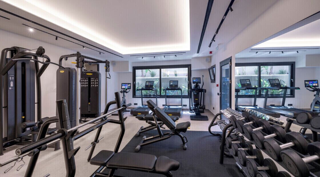 A modern gym with various exercise equipment, treadmills, and dumbbells.