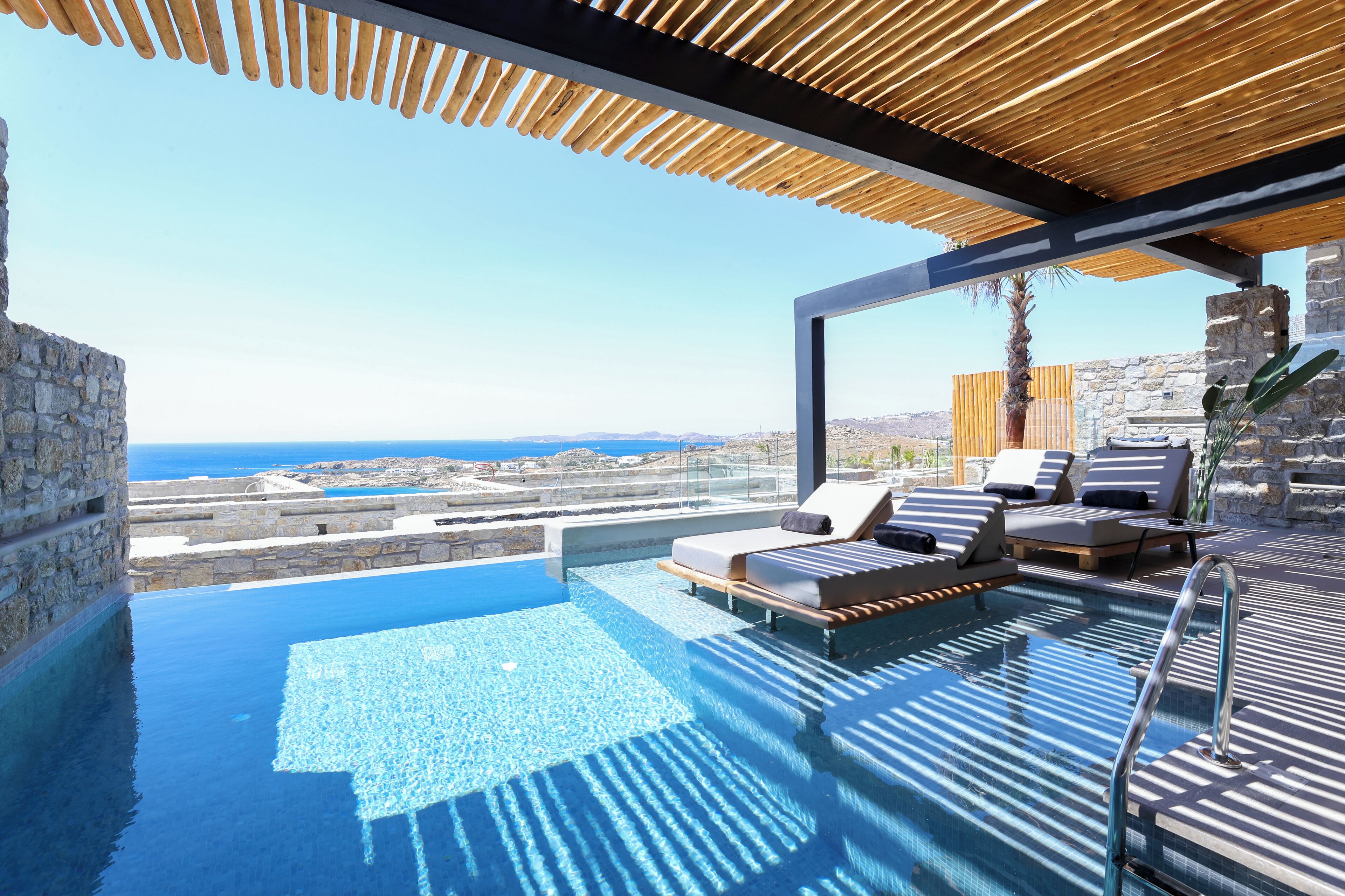 A rooftop infinity pool with lounge chairs and a view of the sea.