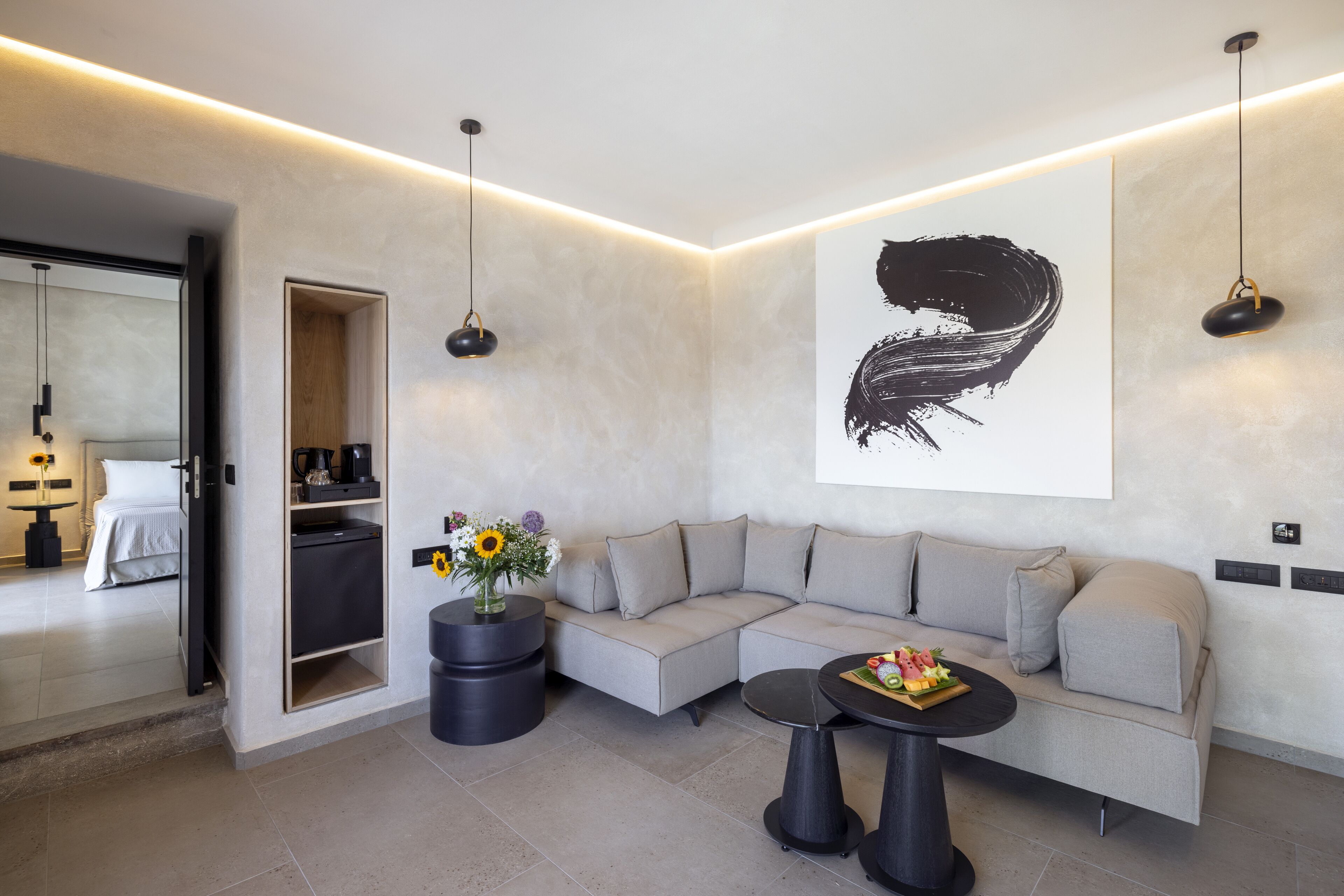 A modern living room with a sofa, a coffee table with fruit, a vase with flowers, and a large abstract painting on the wall.