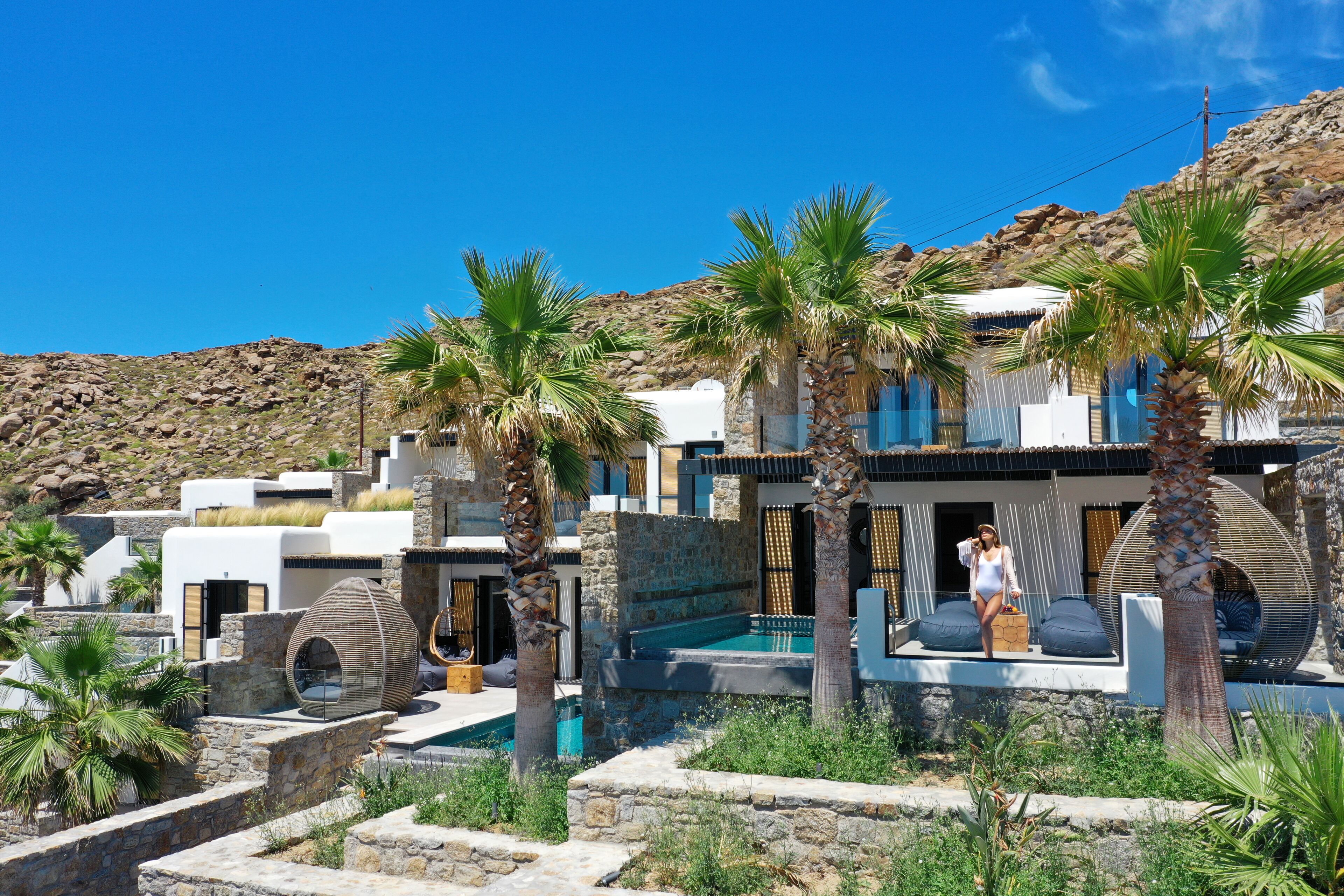 Une villa moderne avec des murs en pierre, une piscine et des palmiers.