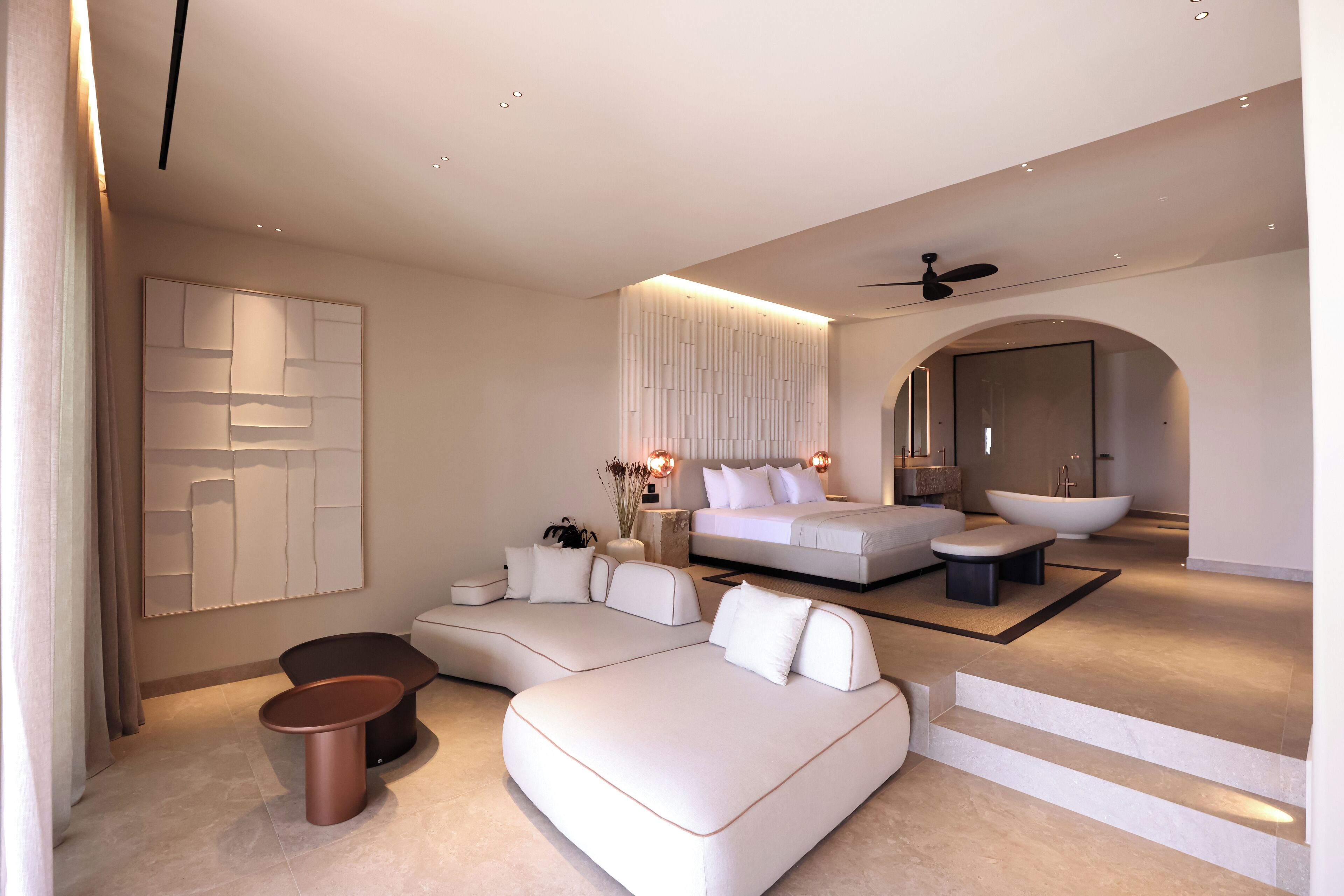 A modern bedroom with a large bed, a sofa, and a seating area.