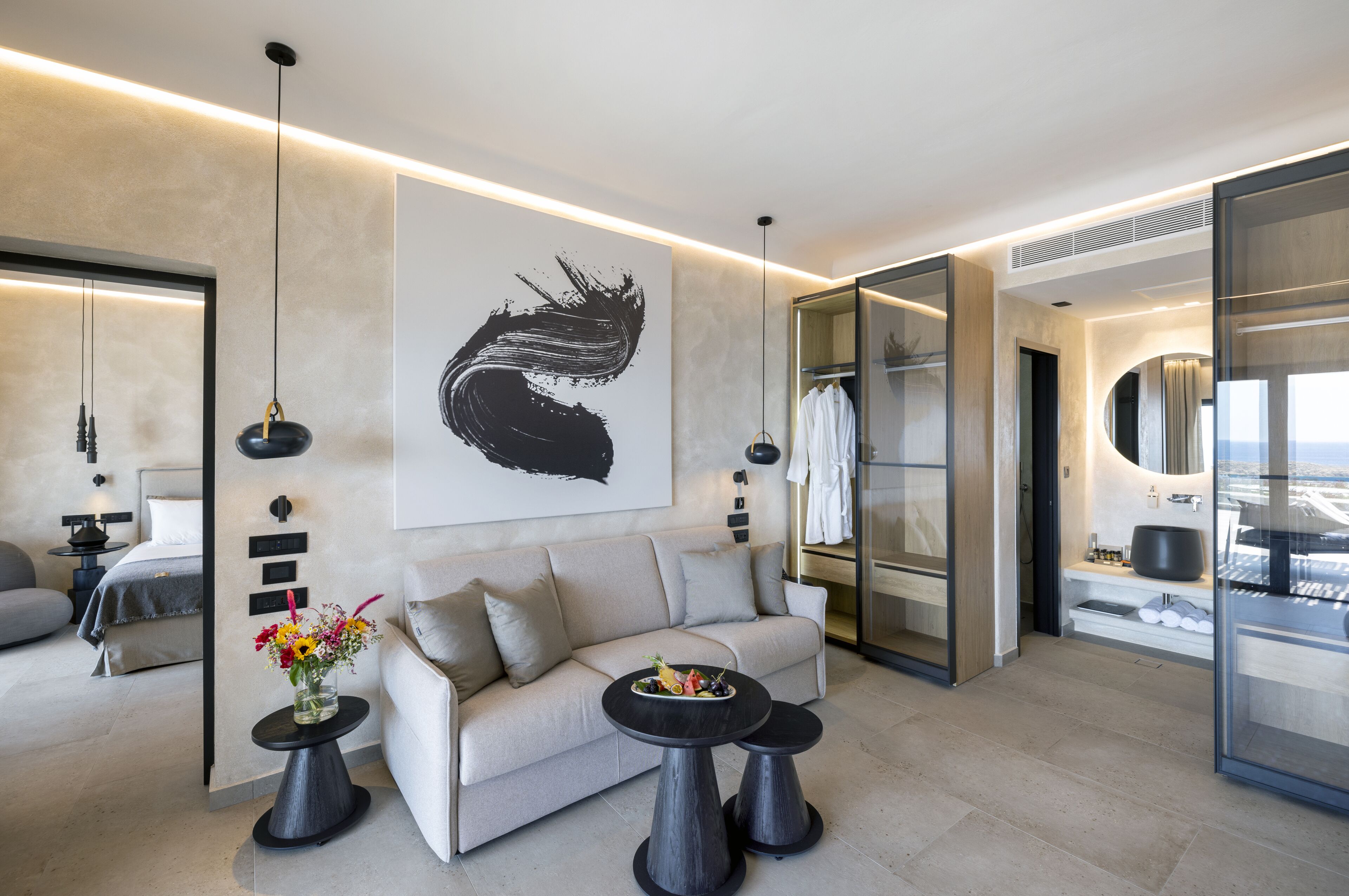 A modern hotel room with a sofa, two side tables, a large abstract painting, and a view of the city.