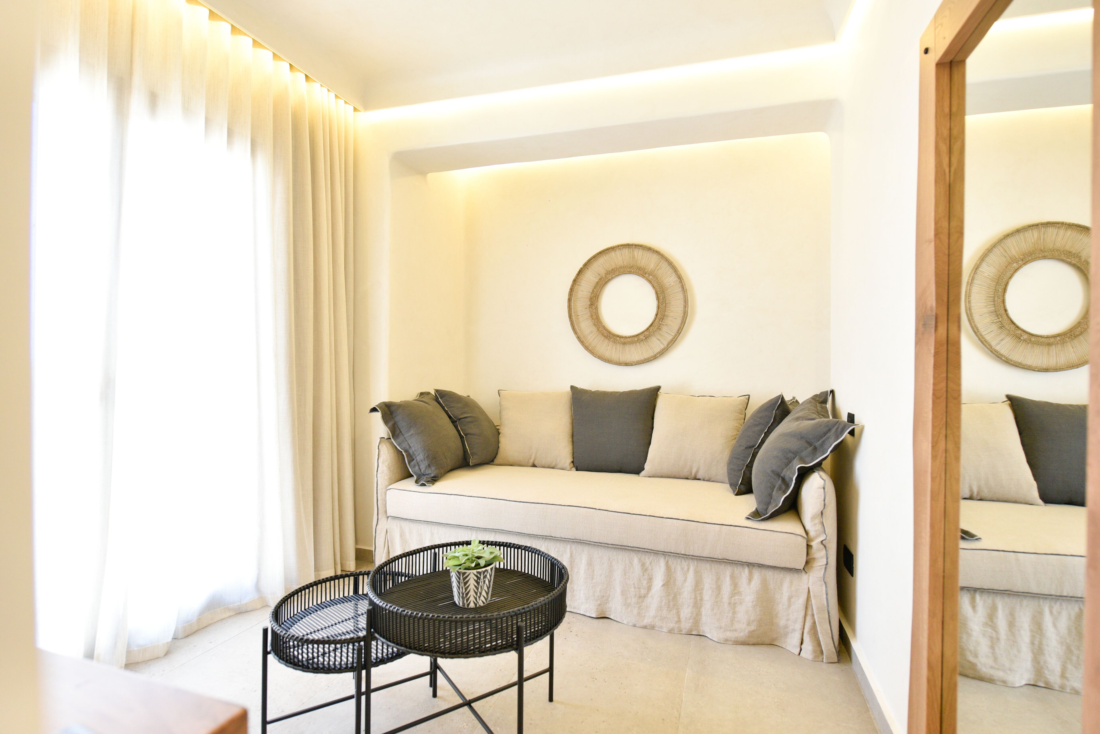 A modern living room with a sofa, a round coffee table, and a large mirror.