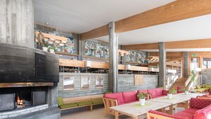 Un espace intérieur vaste et accueillant, doté d’une cheminée, de poutres en bois, de différents coins salon et d’œuvres d’art accrochées aux murs.