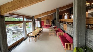 Une pièce spacieuse avec une longue table en bois et des chaises, un canapé rouge et un mur en pierre.