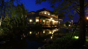 Une maison moderne avec une piscine, entourée d’arbres et éclairée par un système d’éclairage d’ambiance.