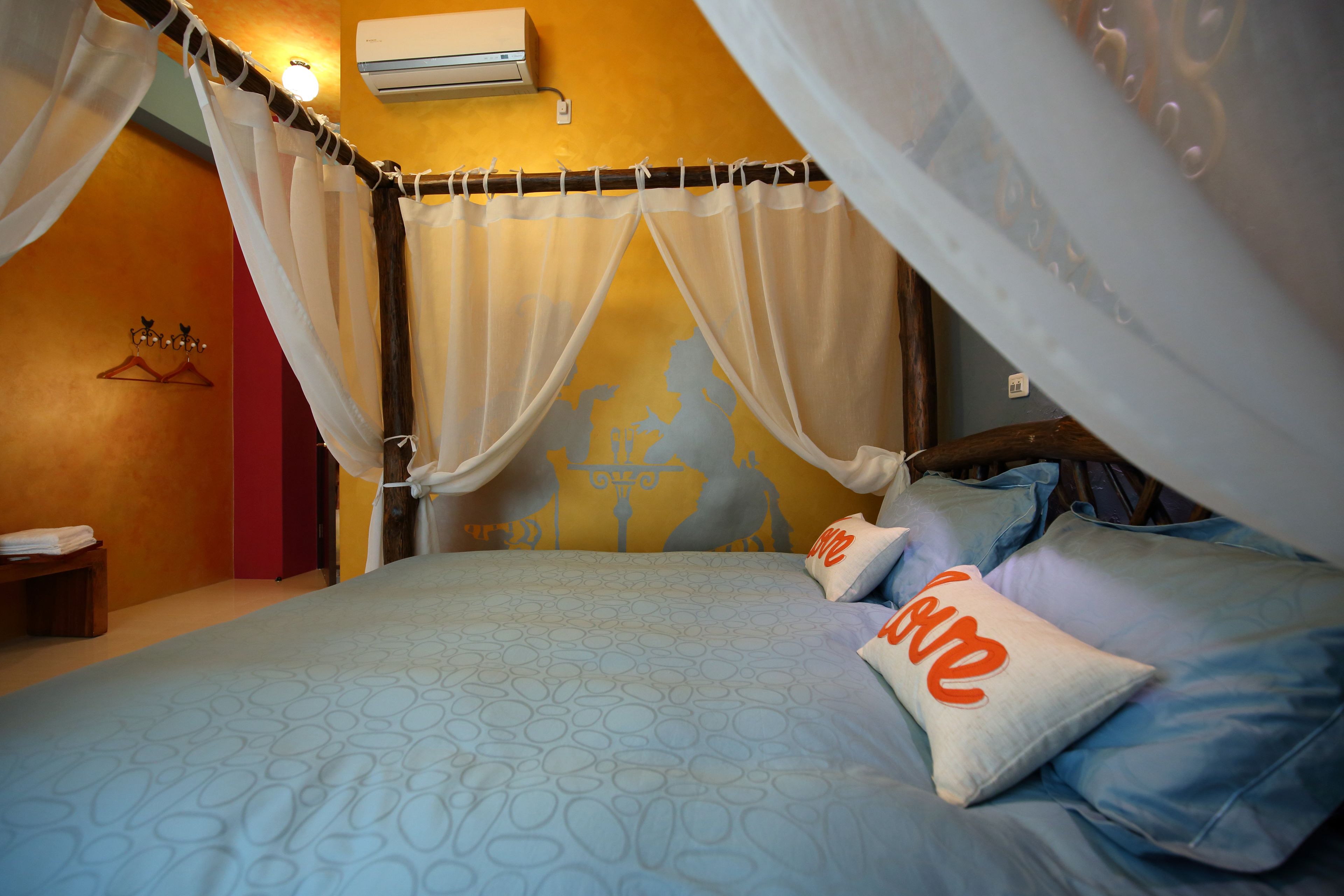 A bed with a canopy, pillows with 'love' written on them, and a wall with a globe design.