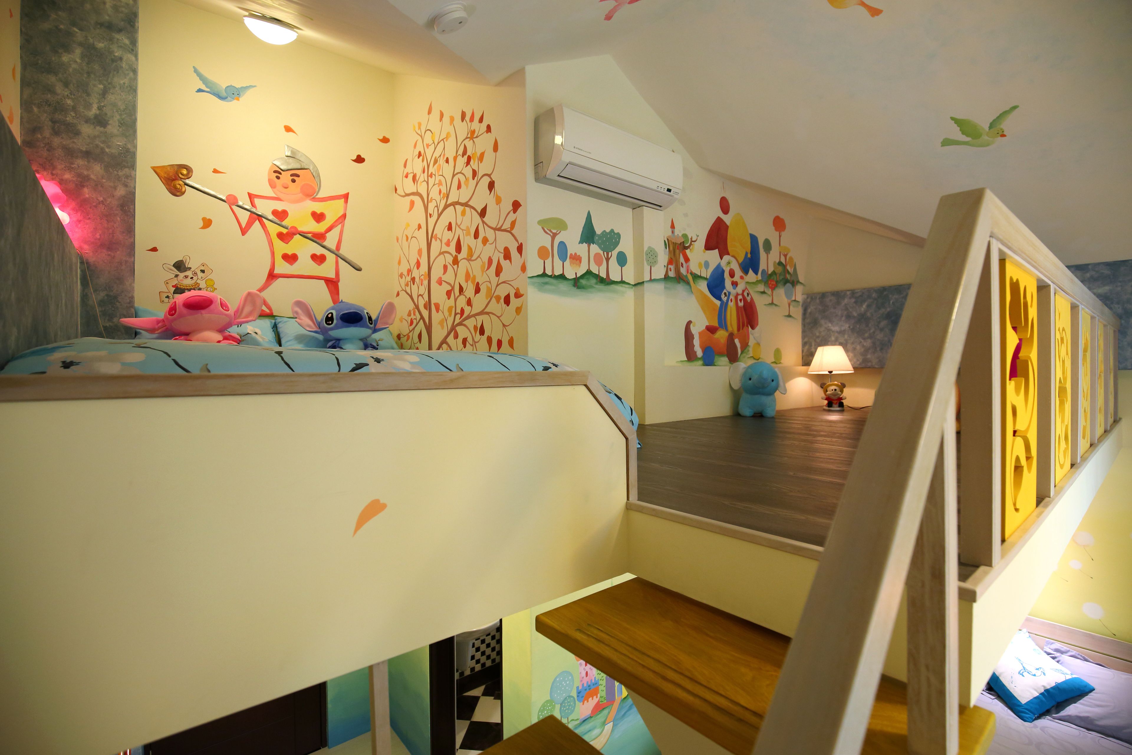 Habitación infantil con literas, decoraciones coloridas en la pared y una mesita con lámpara.