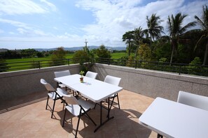 A patio with a white table and chairs, a potted plant, and a view of greenery and mountains. - The Wonderland B&B (Ji'an)