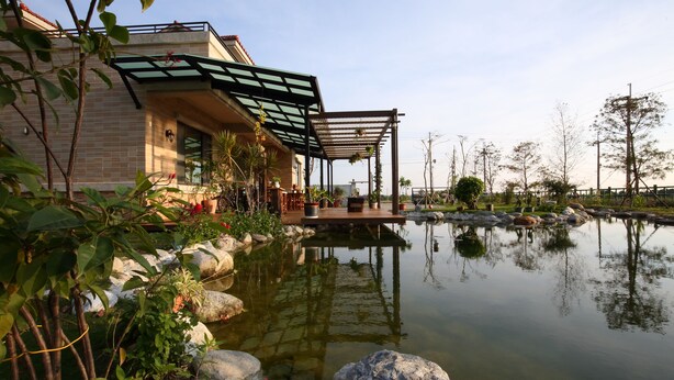 Une maison moderne dotée d’un jardin, d’un étang et d’une pergola.