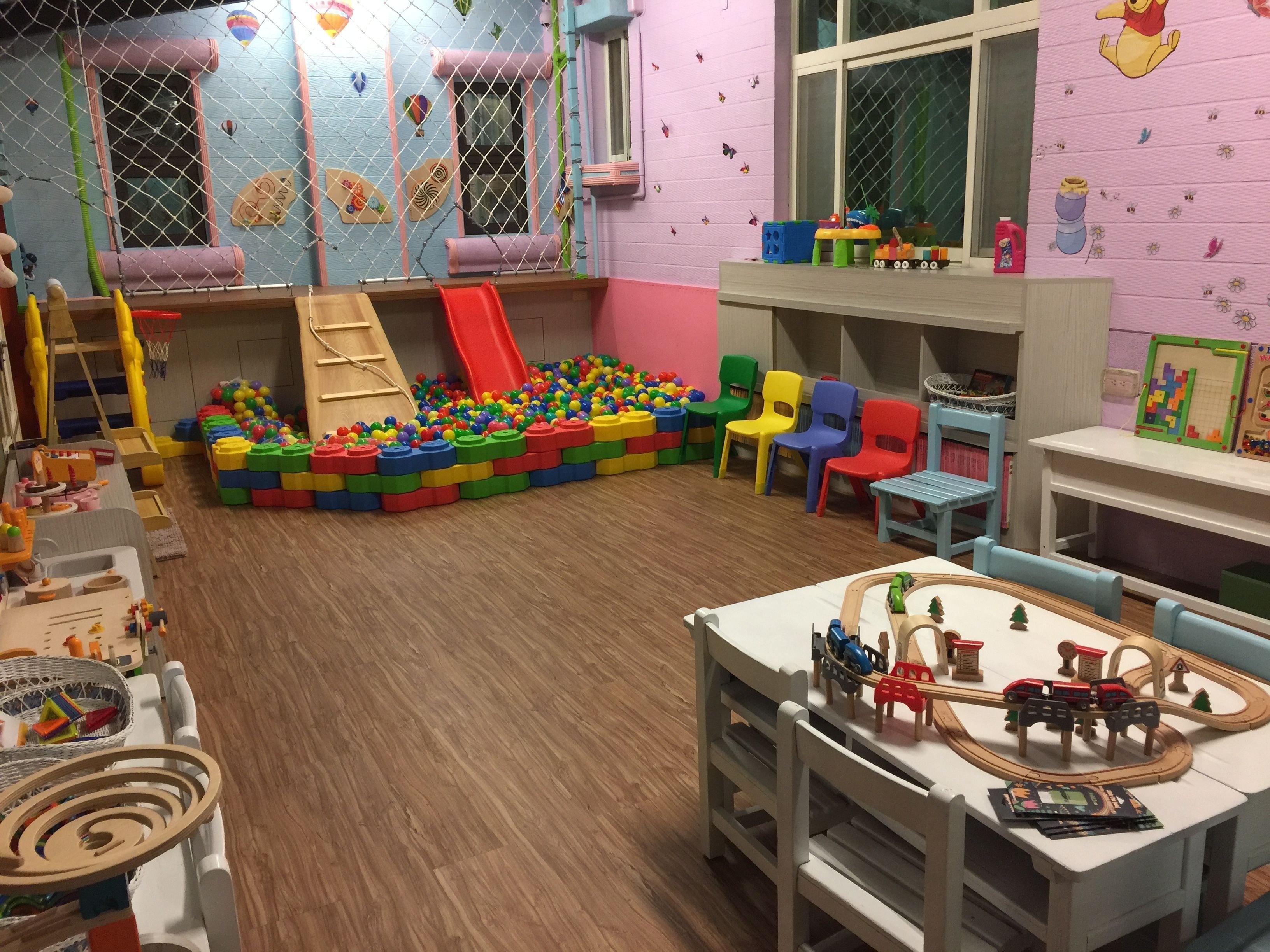 A playroom with a ball pit, a slide, and a train set.