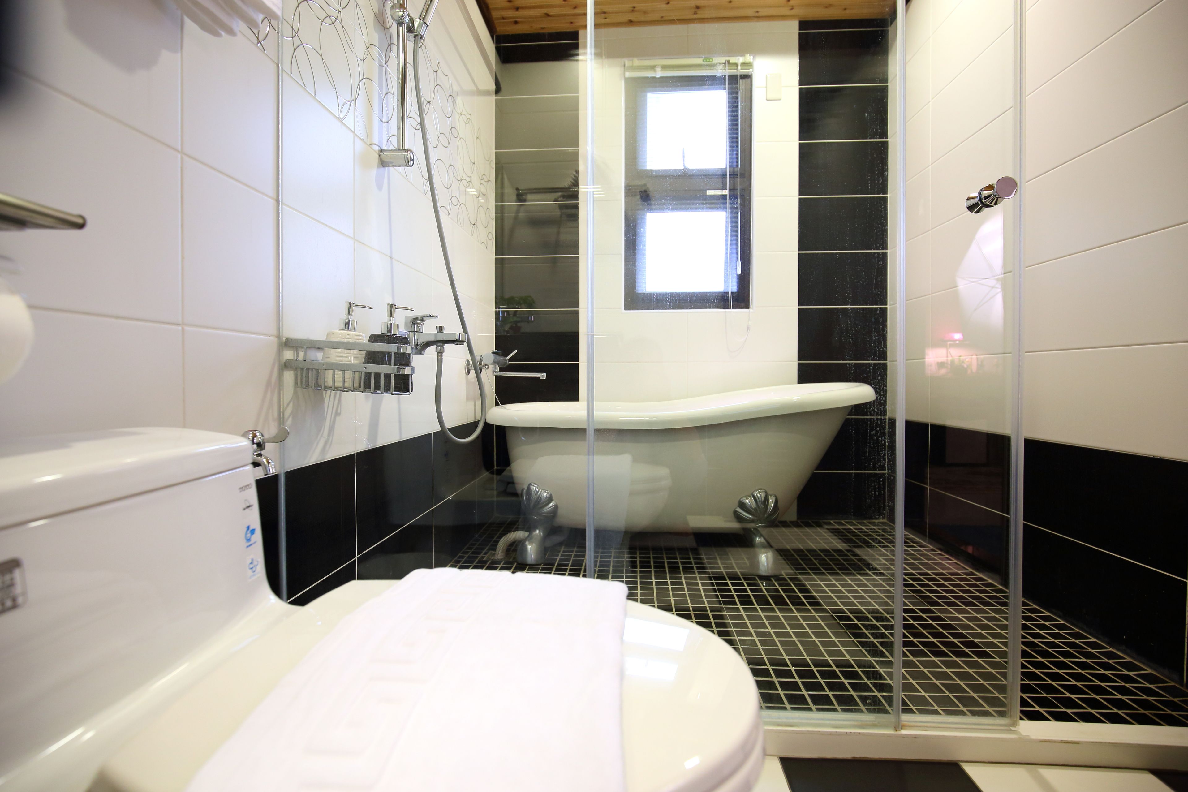 A modern bathroom with a white toilet, a glass-enclosed shower, and a bathtub.