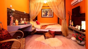 A room with a bed, a vanity with candles, a chair, and a vase with flowers. - Sweet Heart Hostel (Hualien City)