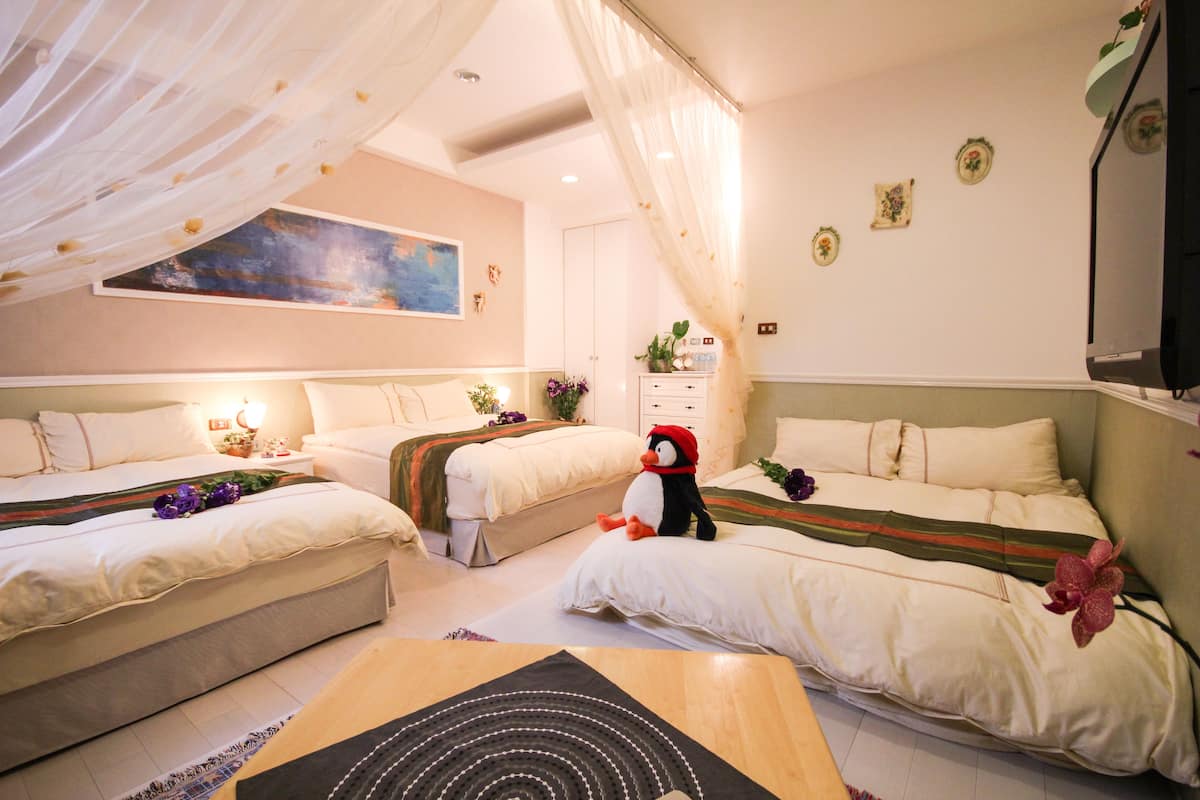 A hotel room with two beds, a large painting on the wall, a TV, and a decorative plant.