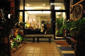Una entrada luminosa con un amplio ventanal, un banco de madera y varias plantas en macetas.