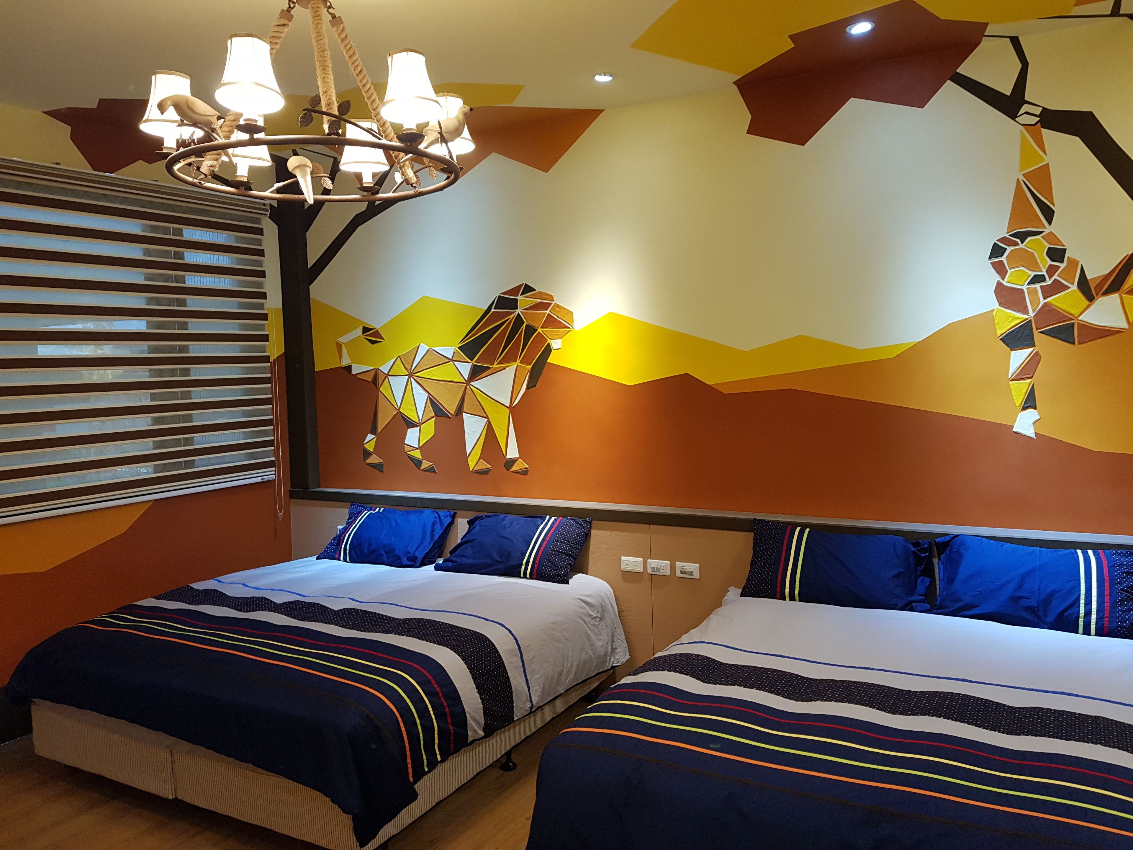 A room with two beds, a chandelier, and a wall mural.