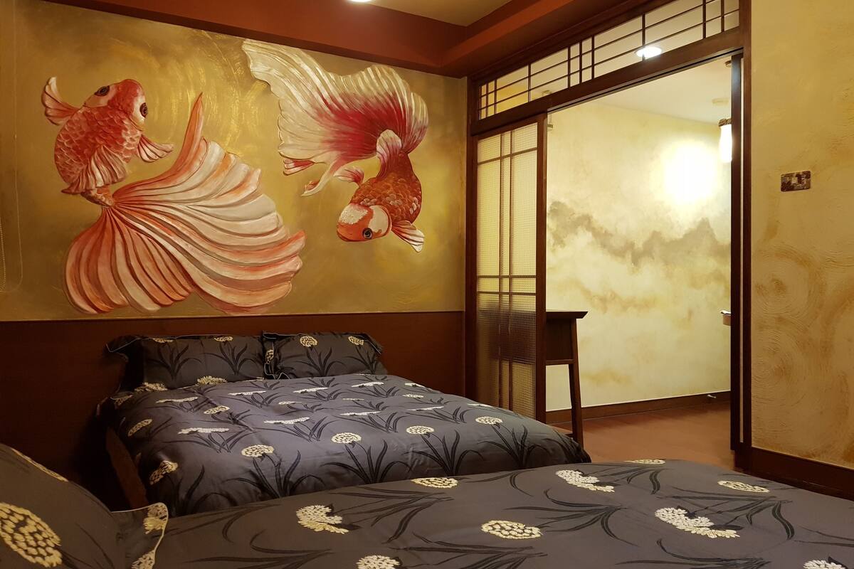 A bedroom with a bed, a wall painting of fish, and a sliding door.