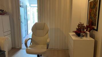 A modern office space with a white office chair, a desk, and a small side table with decorative items.