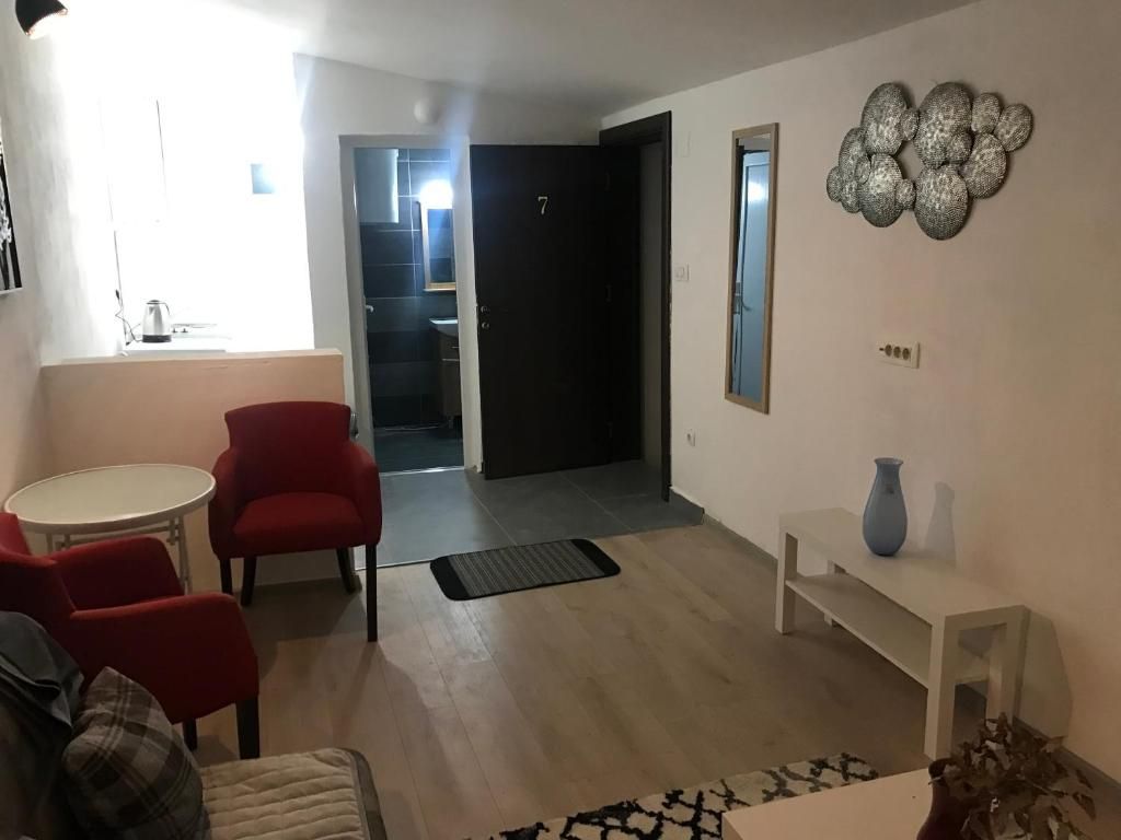 Ein Wohnzimmer mit einer Couch, roten Sesseln, einem kleinen Tisch und einem dekorativen Wandbild.
