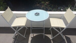 Una mesa redonda pequeña con un bol sobre ella, flanqueada por dos sillas blancas con cojines color beige.