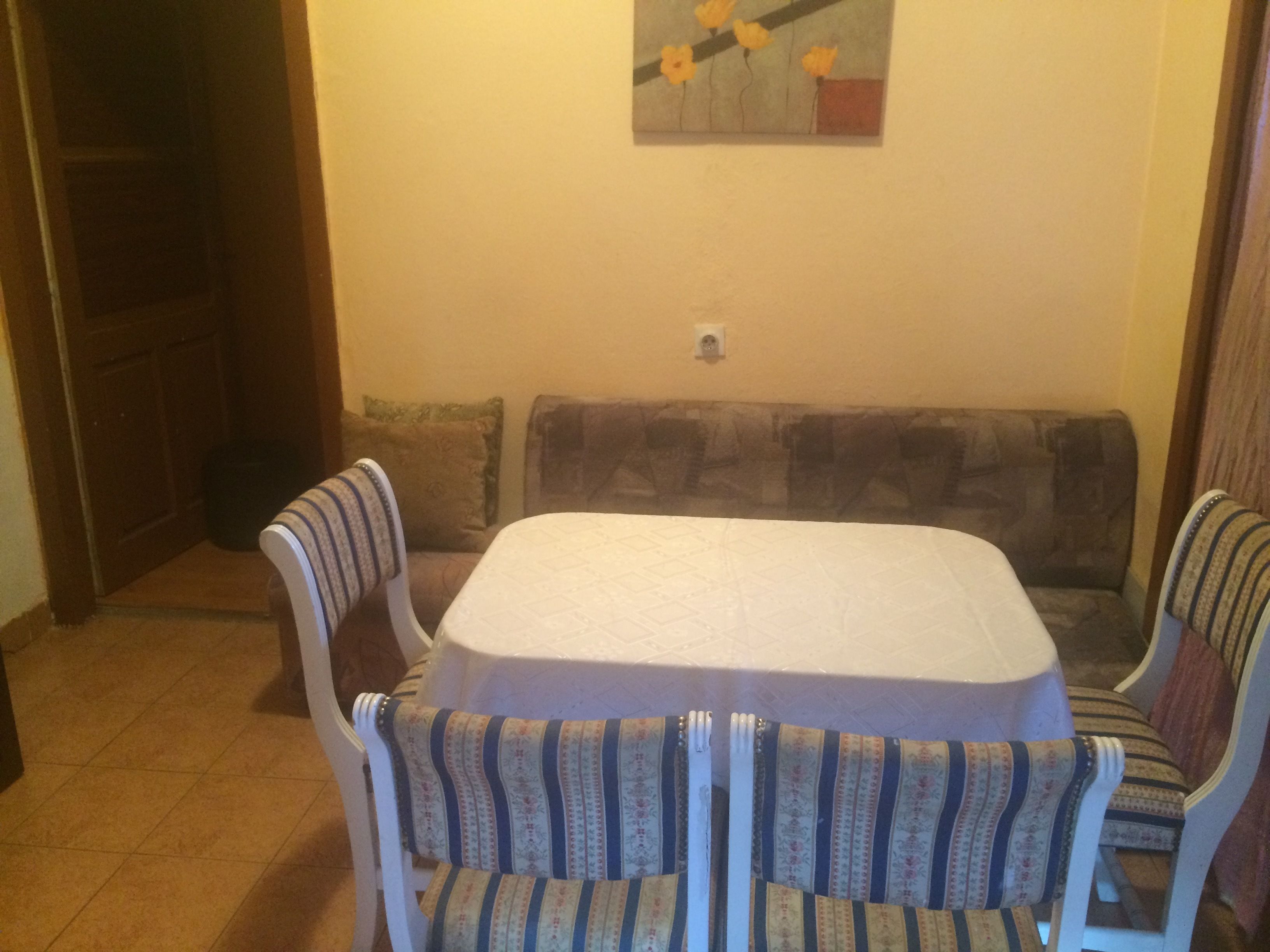 Un comedor con una mesa y cuatro sillas, un sofá y un cuadro en la pared.