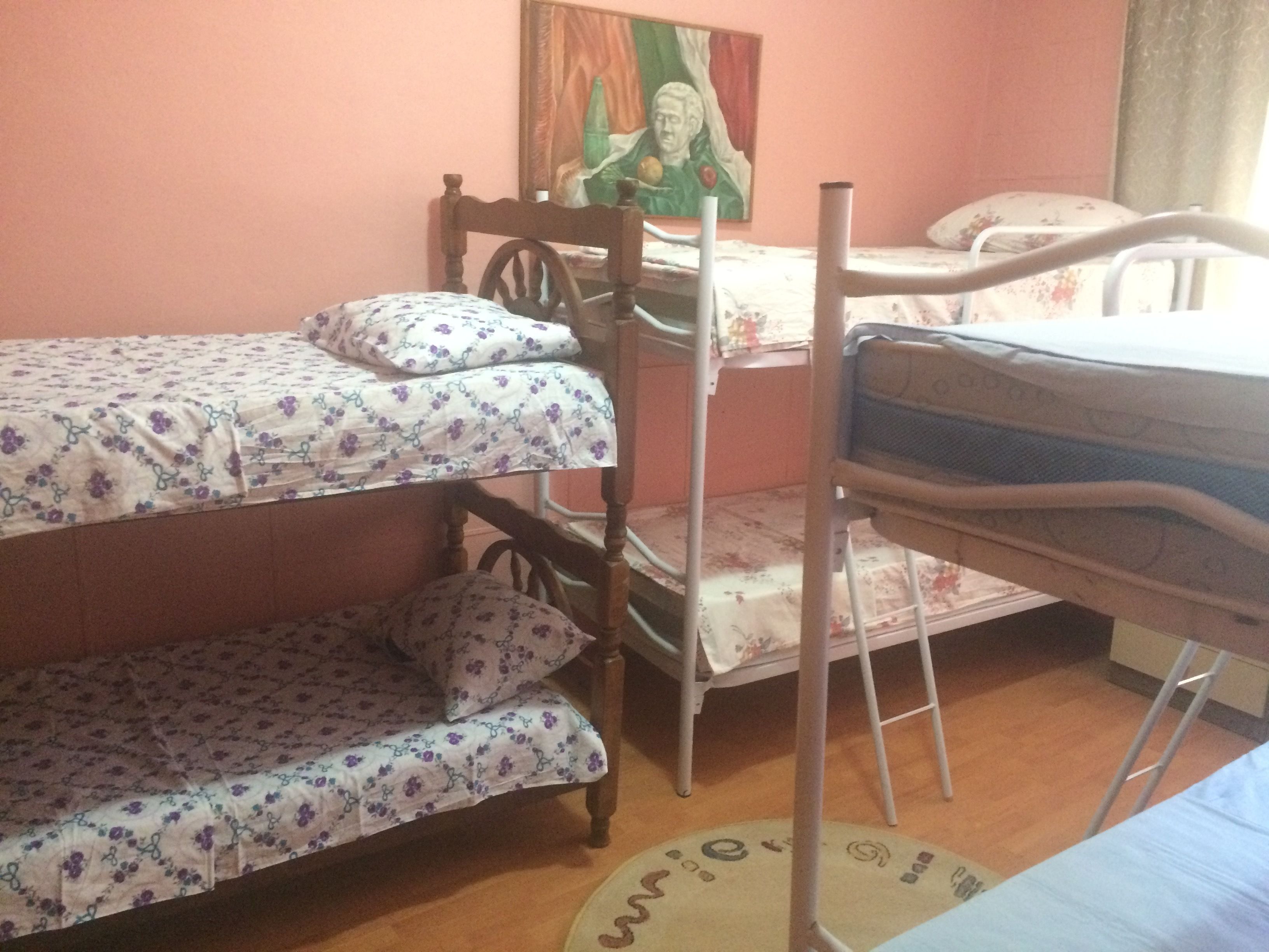 A bunk bed room with floral bedding and a painting on the wall.
