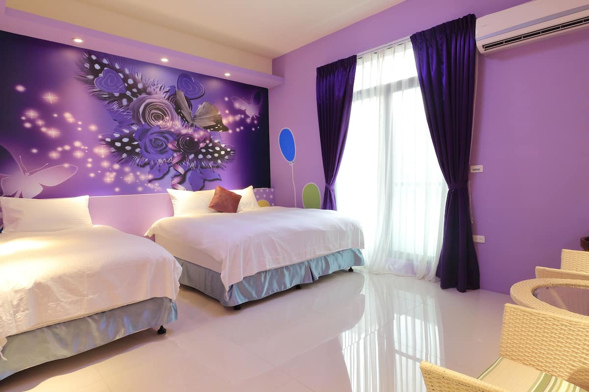 Una habitación con dos camas, un mural grande en la pared y una silla de mimbre.