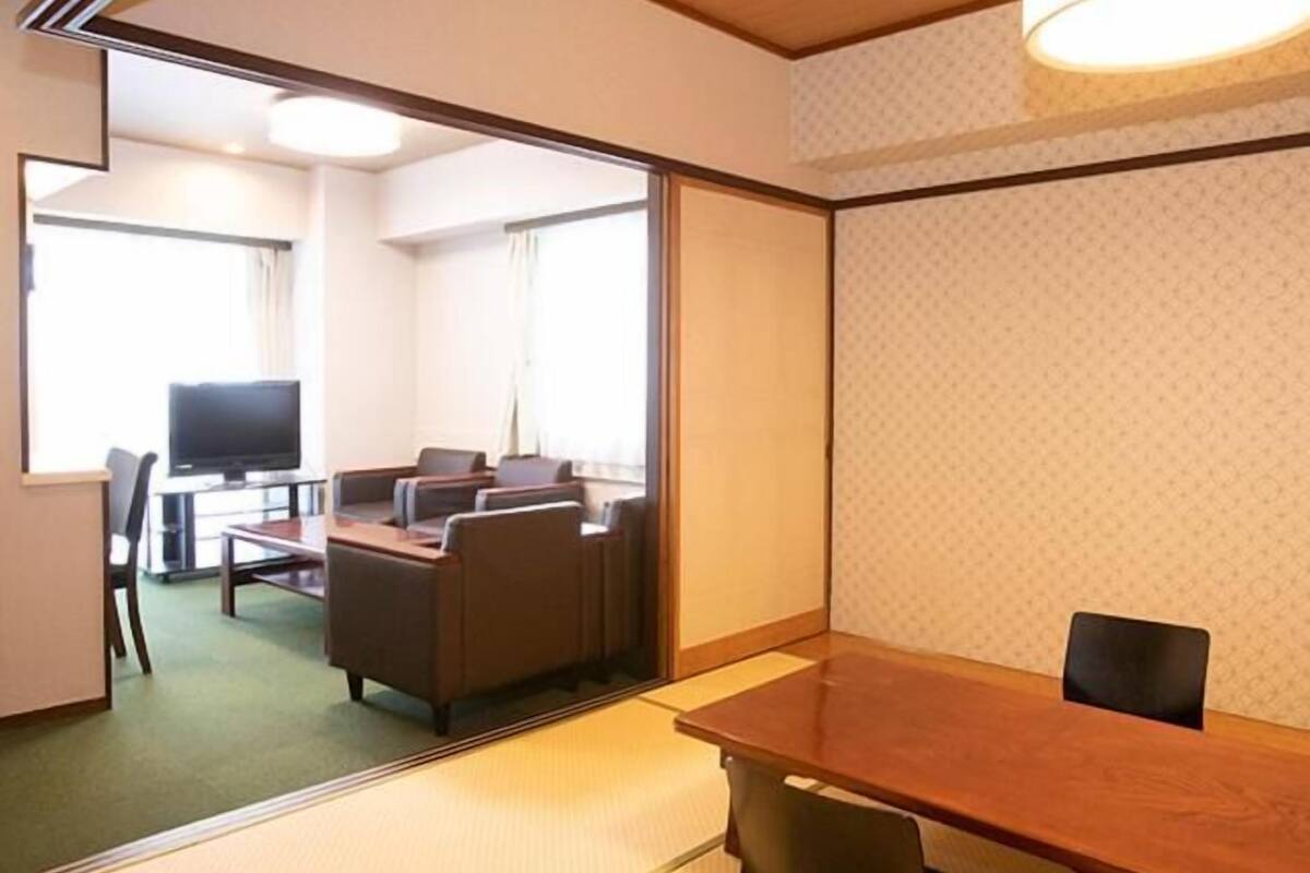 Una habitación de hotel con una mesa de madera, dos sillas, un televisor y un sofá.