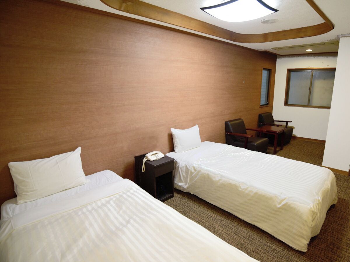 Una habitación de hotel con dos camas, un escritorio, una silla y un teléfono.