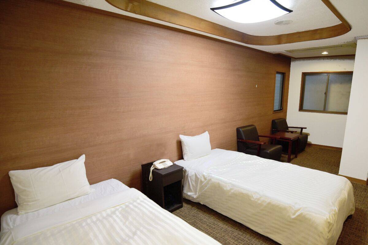 Una habitación de hotel con dos camas, un escritorio, una silla y un teléfono.