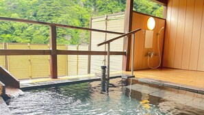 Un área de aguas termales con una terraza de madera, una pequeña piscina y una estructura tipo cabaña de madera.