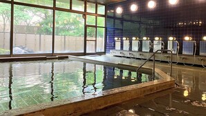 Una piscina interior con paredes de vidrio transparente, suelo de baldosas y varias luces colgantes.
