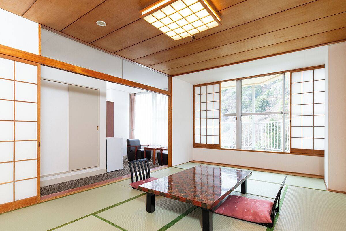 Ett traditionellt japanskt rum med tatamimattor på golvet, ett lågt träbord och skjutdörrar.