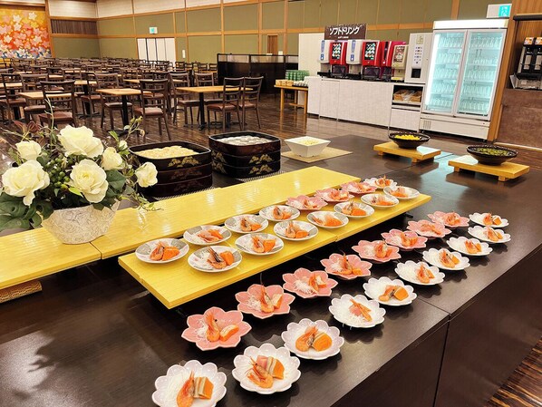 A buffet setup with neatly arranged plates of food, a floral centerpiece, and a beverage station in the background. - Kinugawa Royal Hotel (Nikko)