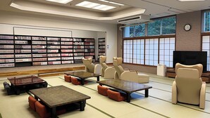 Una biblioteca con suelos de tatami, estanterías, zonas de estar y un televisor.
