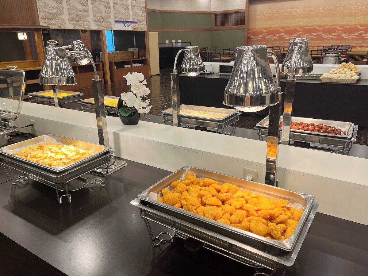 A buffet area with various food items and a decorative vase of white flowers.