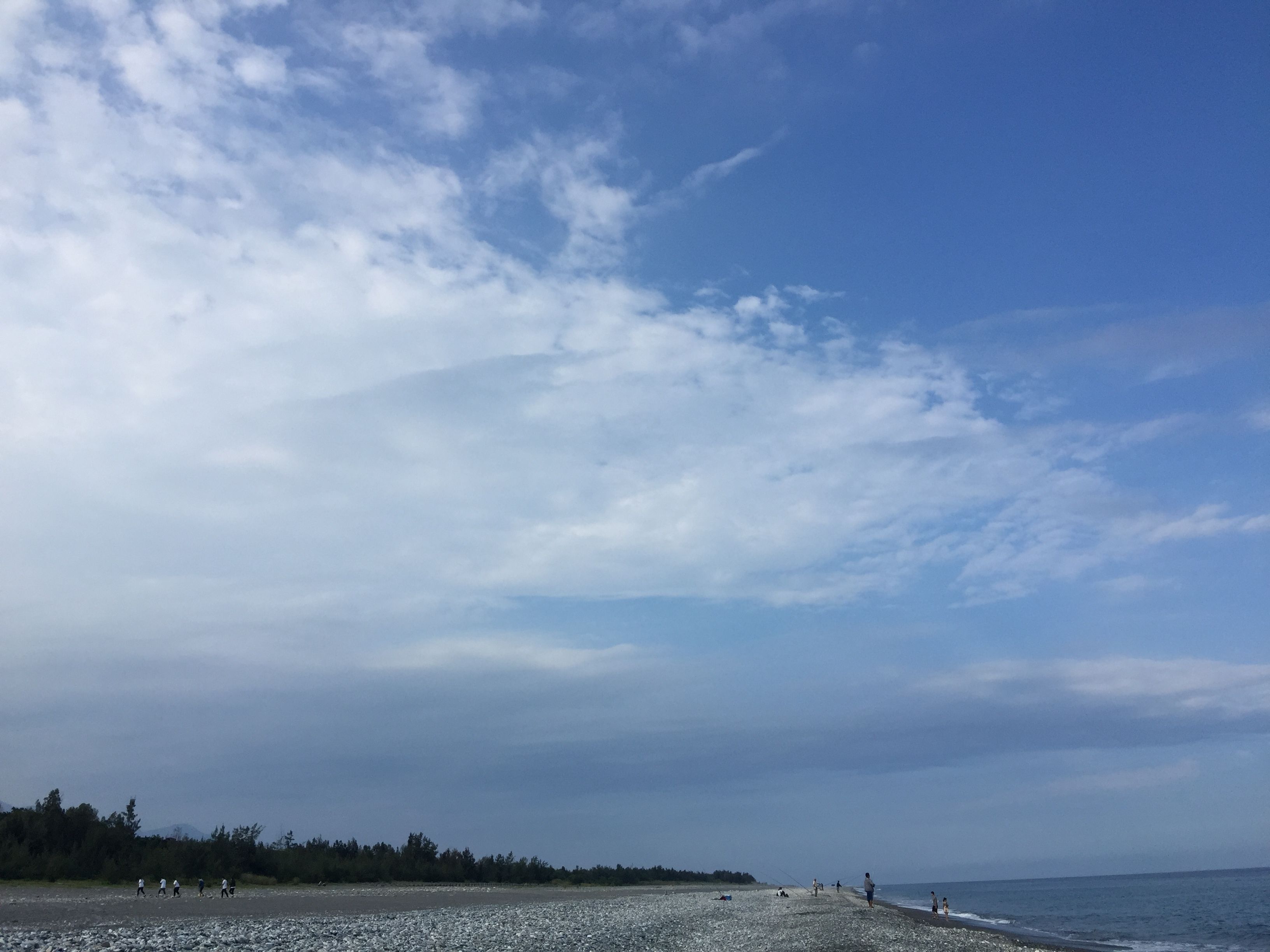 Una playa con costa rocosa, mar tranquilo y cielo despejado.