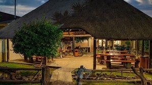 A thatched-roof structure with benches and a pathway leading to it. - Kalahari Arms Hotel (Ghanzi)