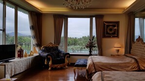Une chambre spacieuse avec un grand lit, un fauteuil, une télévision et une vue sur l’extérieur.