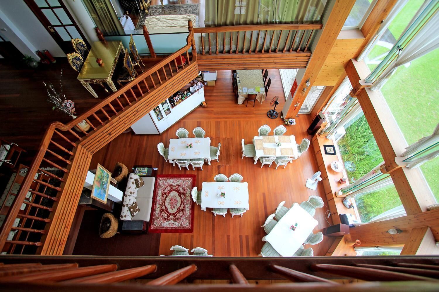 A spacious room with a wooden staircase, multiple dining tables, and a view of the outdoors.